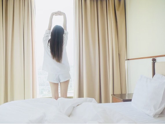 朝日を浴びながら深呼吸する40代女性。体内時計を整え、自律神経をリセットしているイメージ。