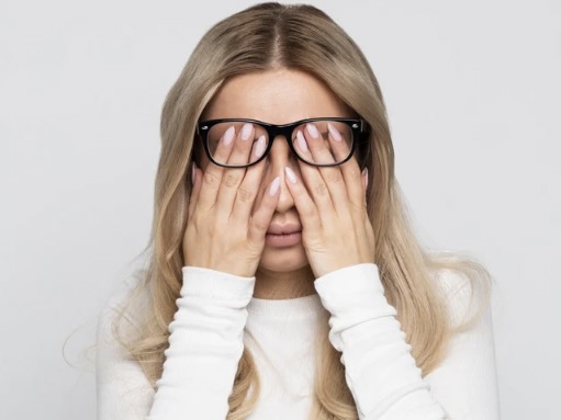寒暖差でだるさを感じる40代女性が、手で顔を覆い疲れている様子。